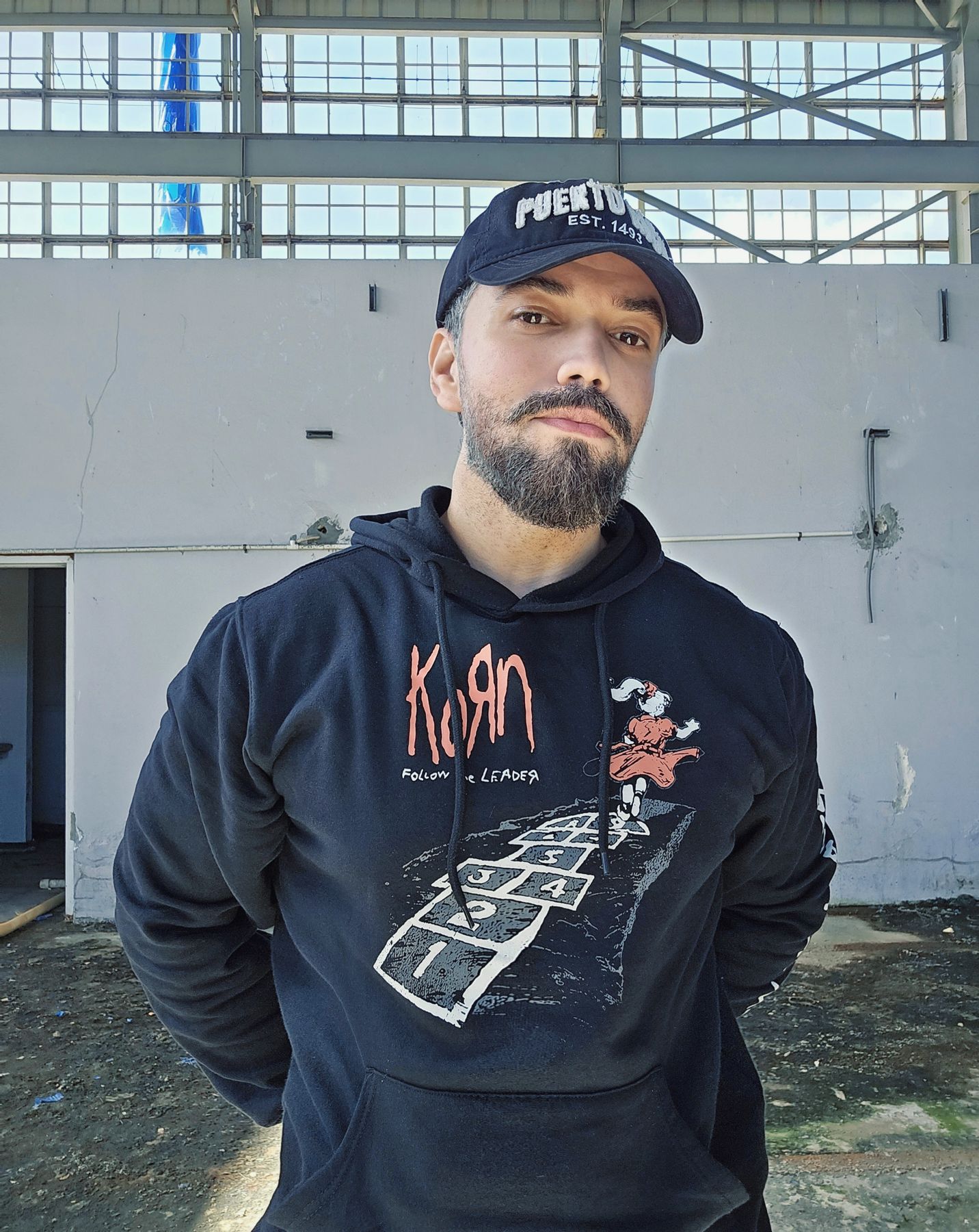 César Romero Reyes de pie frente a la pared de un hangar