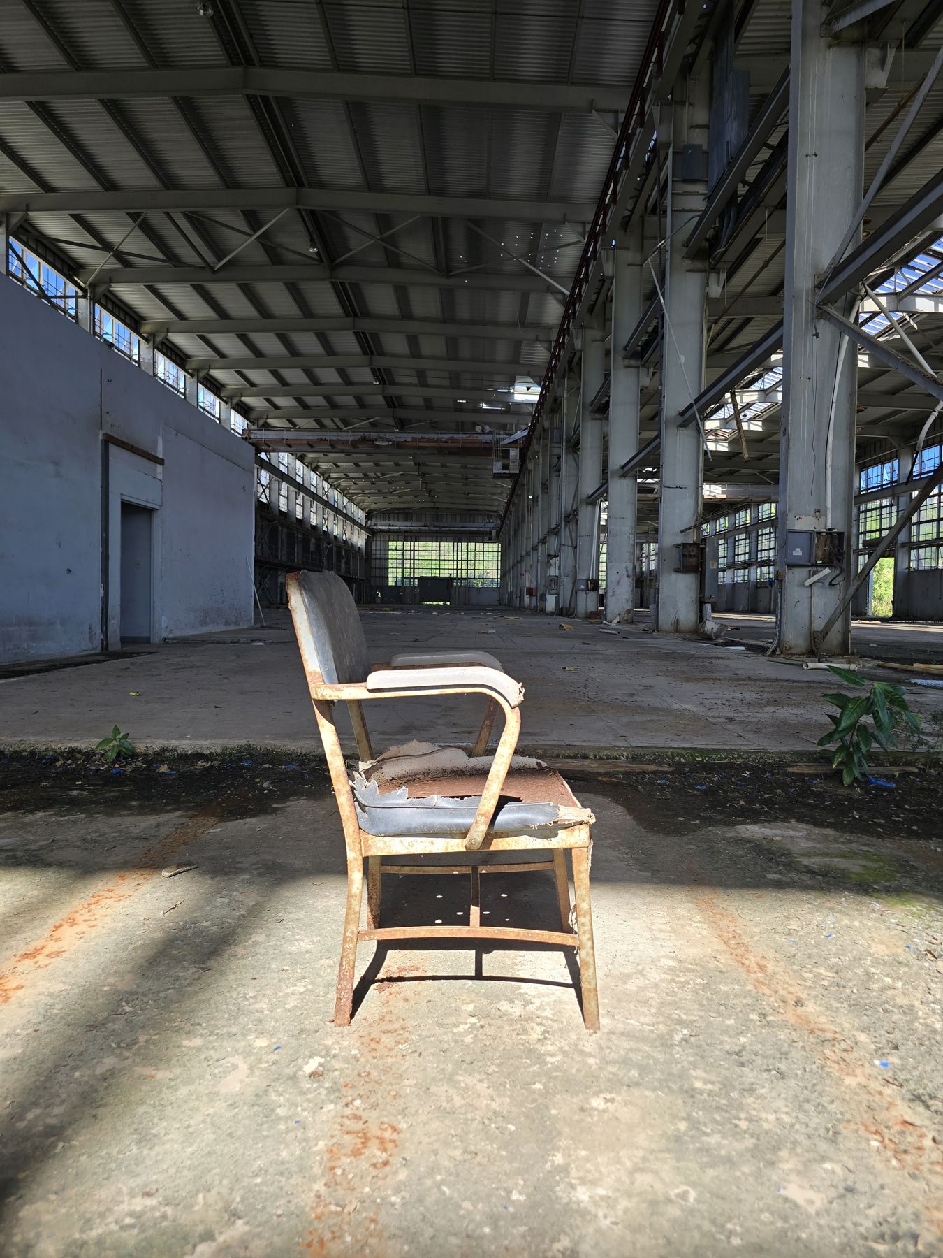 Una silla de oficina oxidada en medio de un hangar vacío