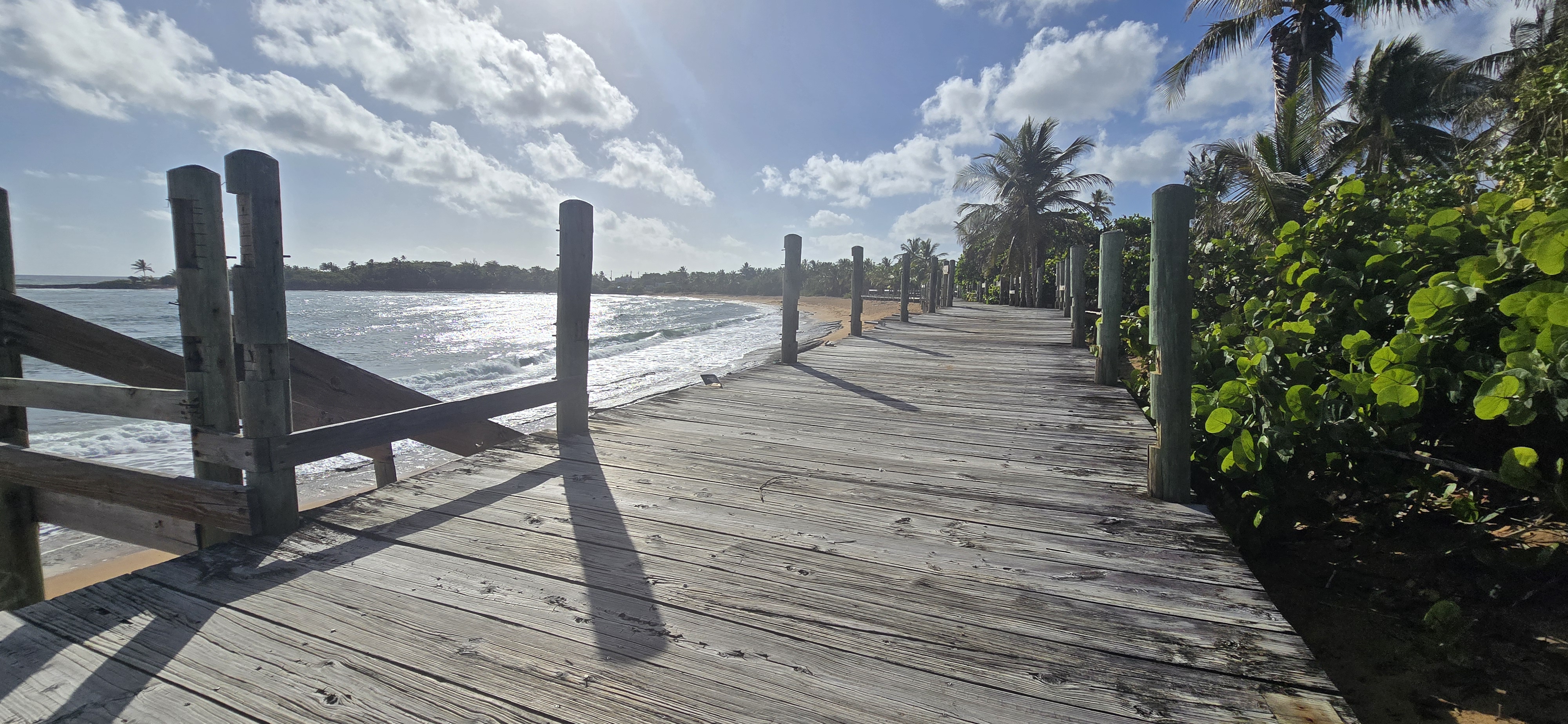 Paseo Lineal Roberto Clemente Walker en Loíza Puerto Rico con mar al fondo y palmeras boardwalk deteriorado
