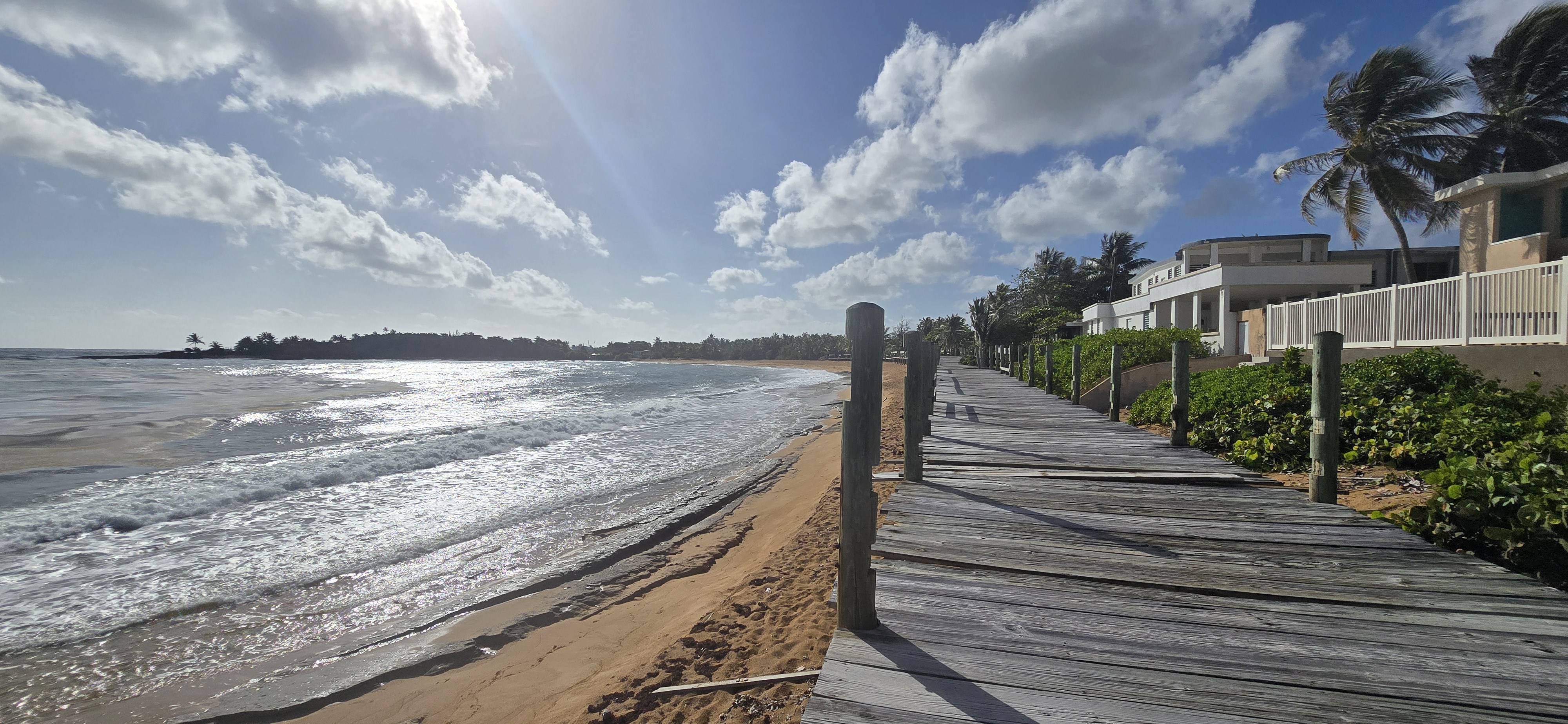 Paseo Lineal Roberto Clemente Walker en Loíza Puerto Rico con el mar al fondo palmeras y casas deteriorado por falta de mantenimiento